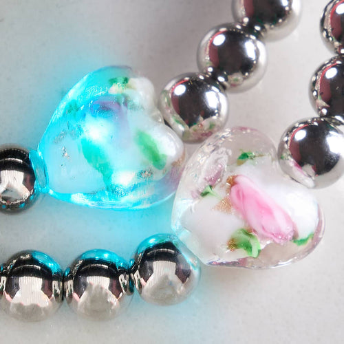 Magnolia glowing hearts essence bracelet close-up showing silver beads and glowing hand-blown firefly glass hearts with floral design by NOGU.